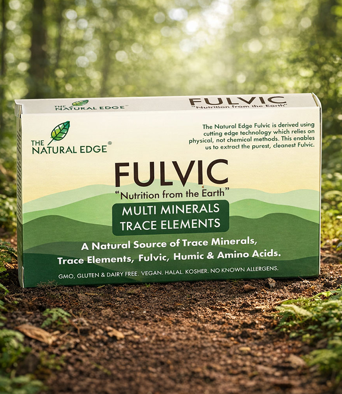 The Natural Edge Fulvic product box displayed outdoors on forest ground with green foliage background.