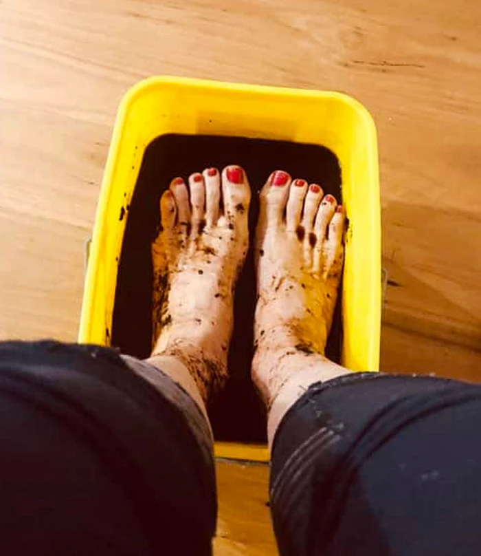 Feet soaking in humic fulvic mineral foot soak solution in yellow tub